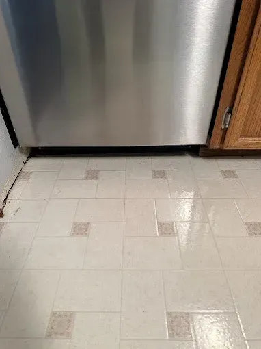 Kitchen floor with white vinyl tiles and a stainless steel dishwasher or refrigerator above it