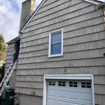 Gray house exterior with a garage door, upper window, and a ladder leaning against the side wall