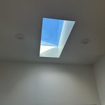 White room ceiling with a rectangular skylight showing blue sky.