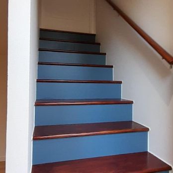 Blue carpeted staircase with wooden steps and a handrail along the wall