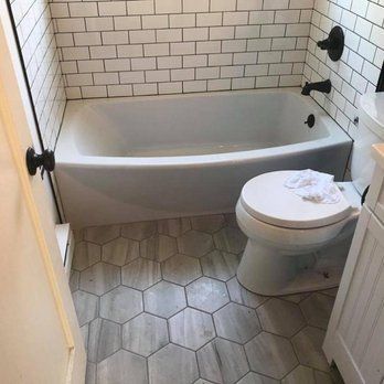 Small tiled bathroom with a white tub, toilet, and hexagonal floor tiles.