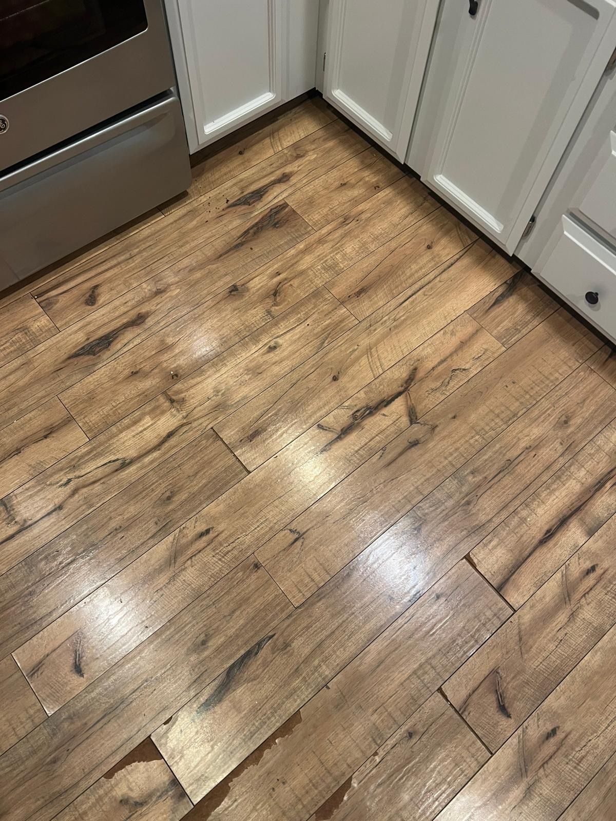 Wooden kitchen floor with cabinets and stainless steel appliance edges visible