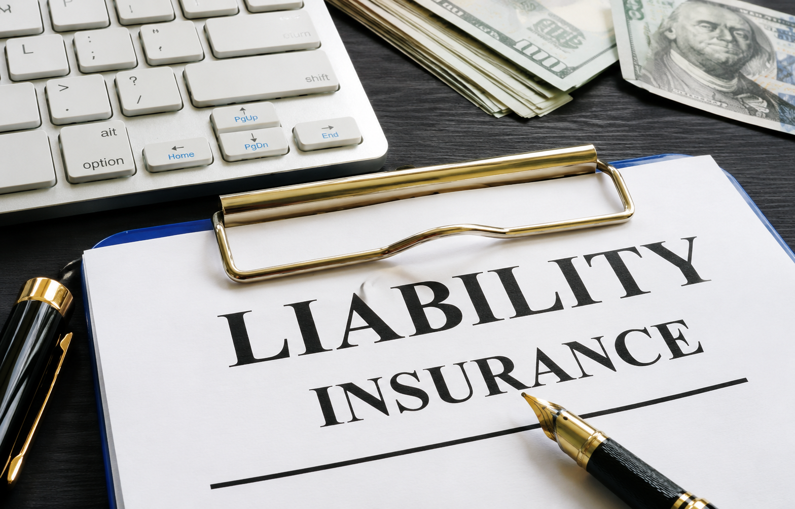 Liability insurance document on clipboard with pen and calculator on desk