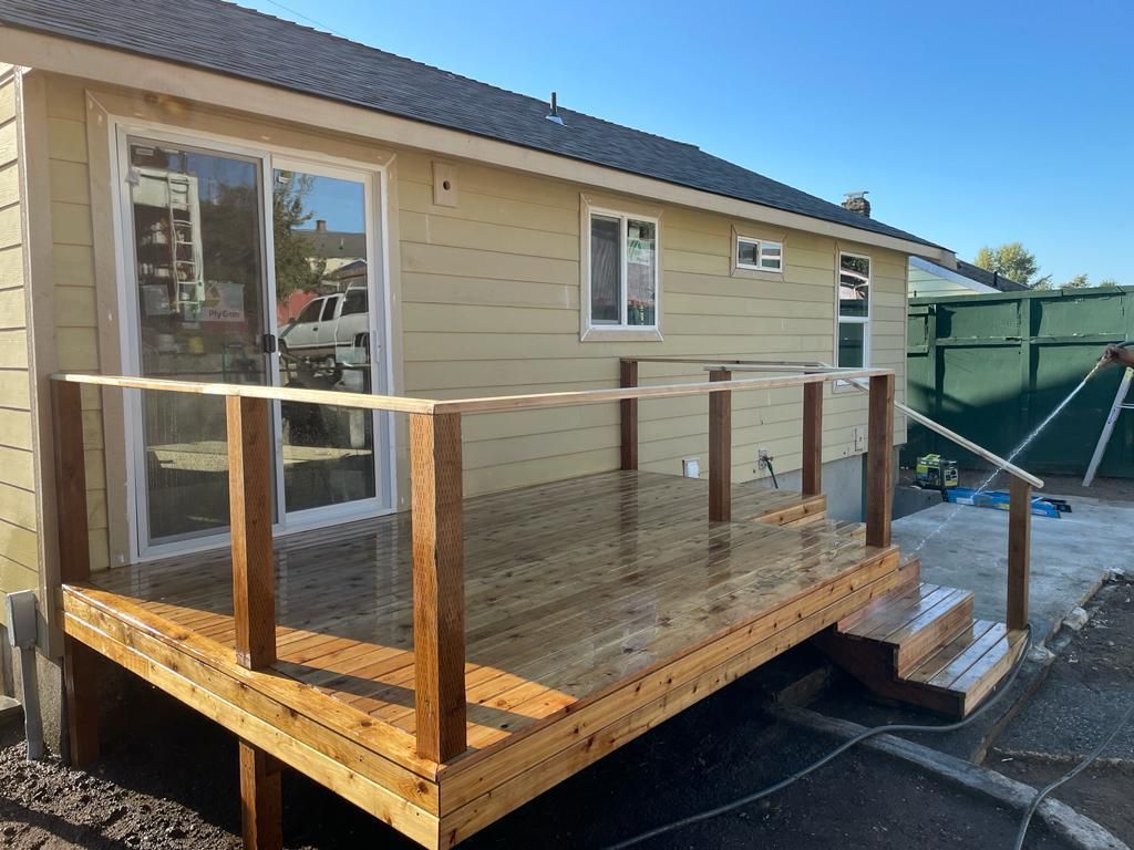 Wooden wheelchair ramp deck beside a beige house, with railings and steps leading down.