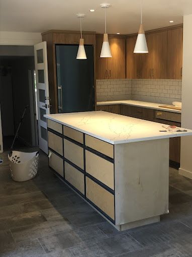 Modern kitchen with island, pendant lights, wood cabinets, and tiled backsplash