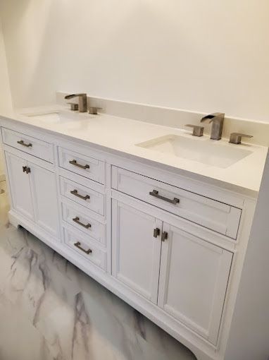 White bathroom vanity with double sink, chrome faucets, and marble-patterned tile floor