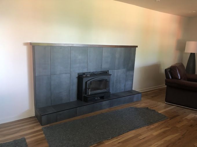 Living room fireplace with dark tile surround, wood floor, and a dark rug in front