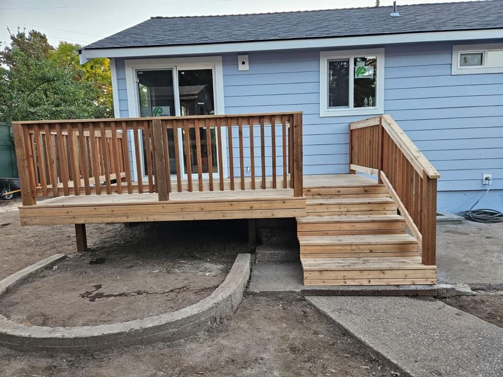 Small blue house with a wooden front porch, ramp, and stairs in a dirt yard