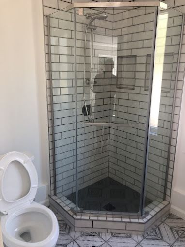Bathroom with glass-enclosed tiled shower and toilet in the foreground