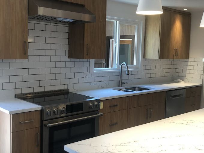 Modern kitchen with dark wood cabinets, white subway tile backsplash, stainless appliances, and a large island