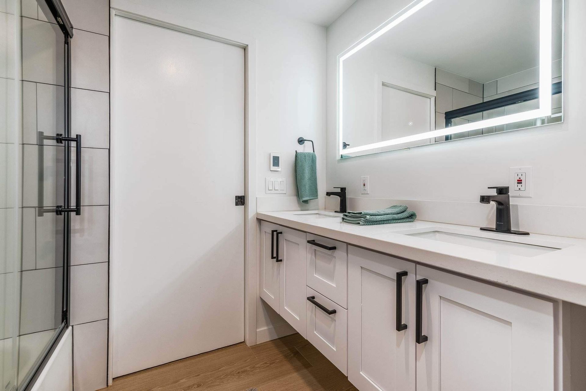 Modern bathroom with white vanity, large mirror, and glass shower door