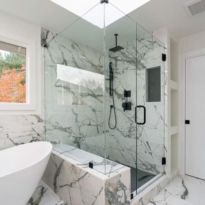 Modern white marble bathroom with glass shower, freestanding tub, and black fixtures