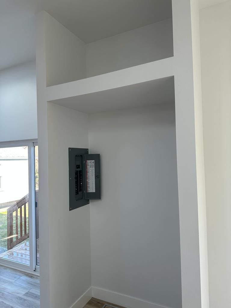 Empty built-in wall niche with gray walls and an electrical panel on the left side