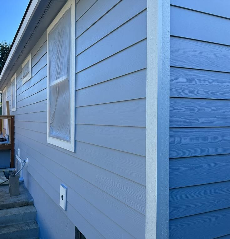 Blue house siding with a window and steps along the side of a home