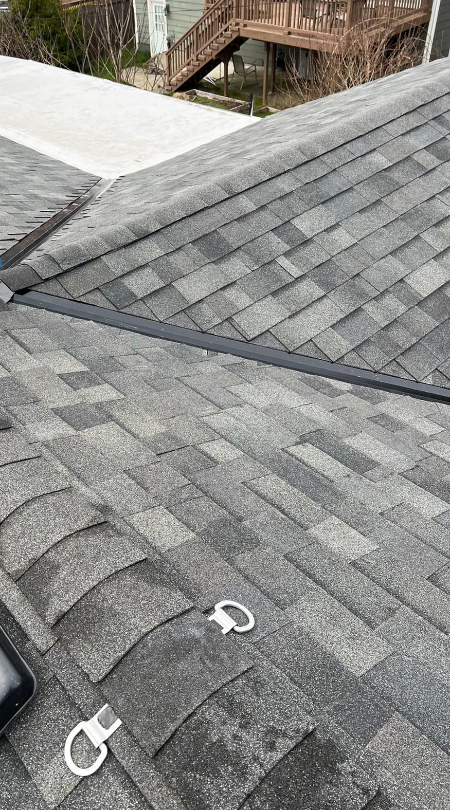 Gray shingled roof with two white metal loops near the bottom, viewed from above.