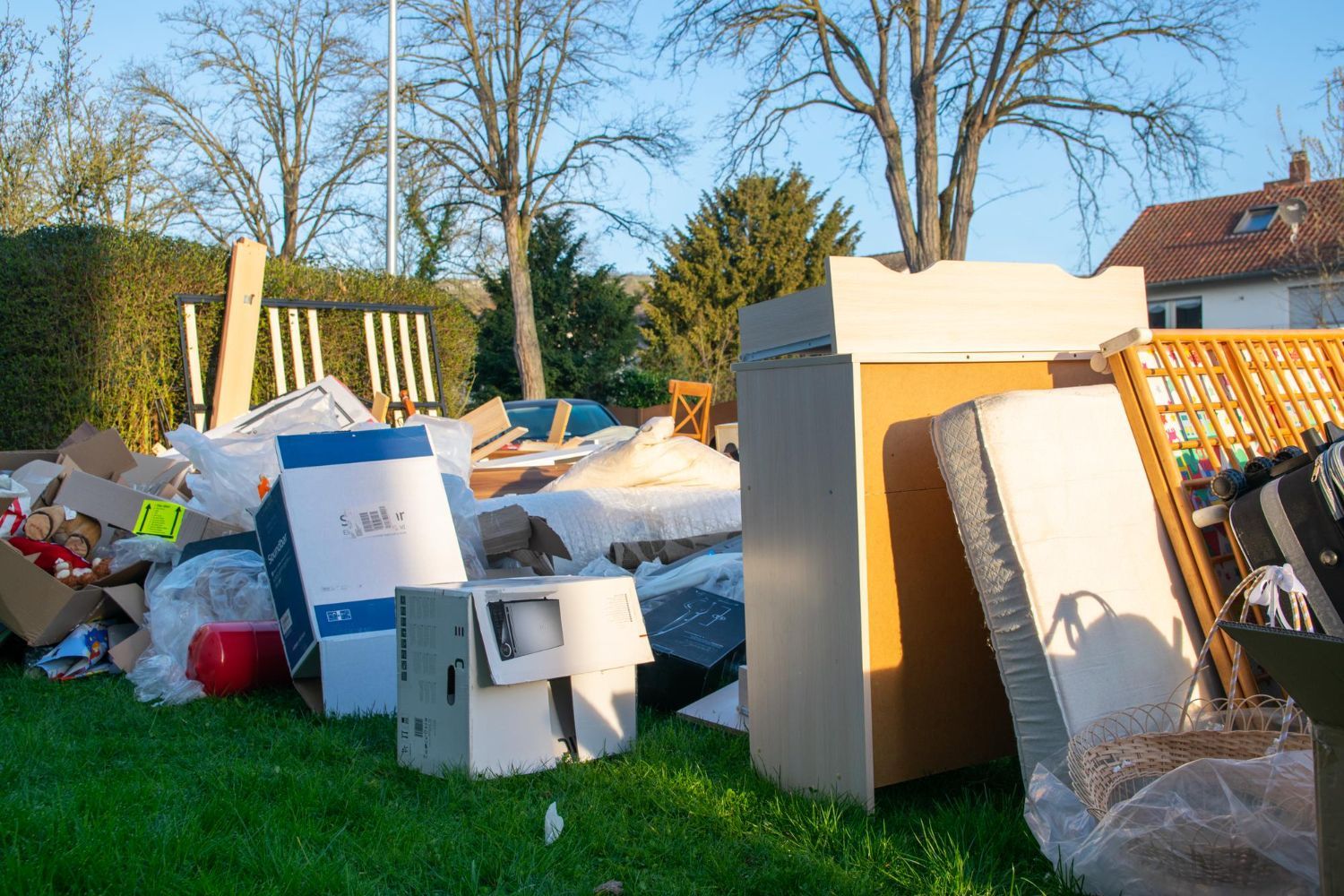 Massive pile of household clutter including a white mattress, wooden dresser, and cardboard boxes on a lawn requiring professional hoarding clean out services in Smyrna GA