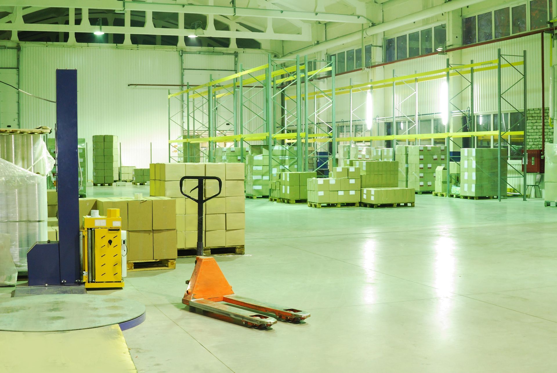 Spacious industrial warehouse floor filled with stacked cardboard boxes metal pallet racking and material handling equipment needing commercial warehouse cleanouts in Smyrna GA