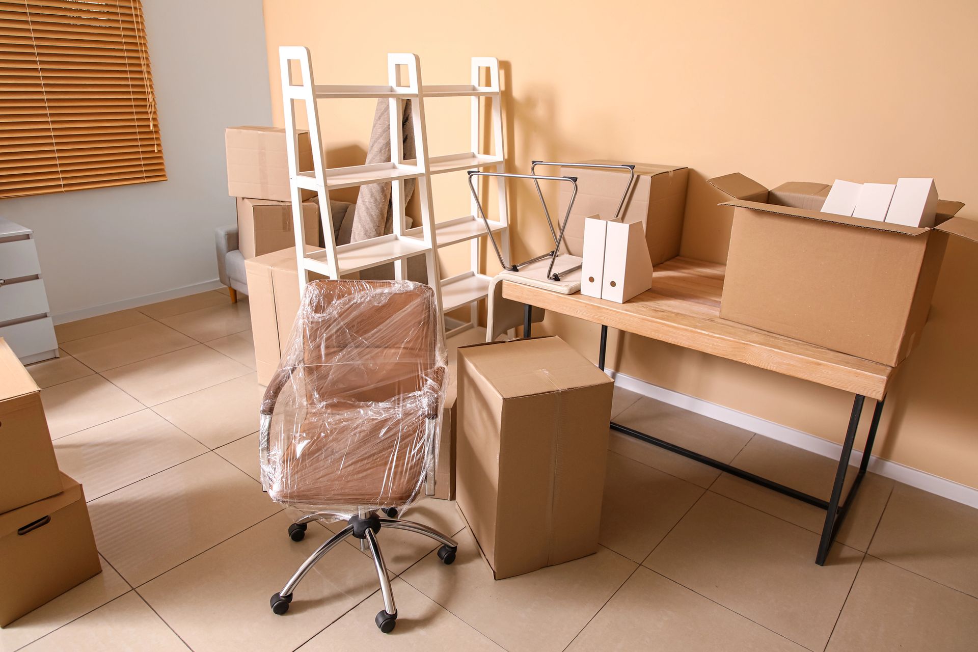 Packed office space filled with cardboard boxes a shrink wrapped desk chair and wooden furniture needing property management cleanout services in Smyrna GA