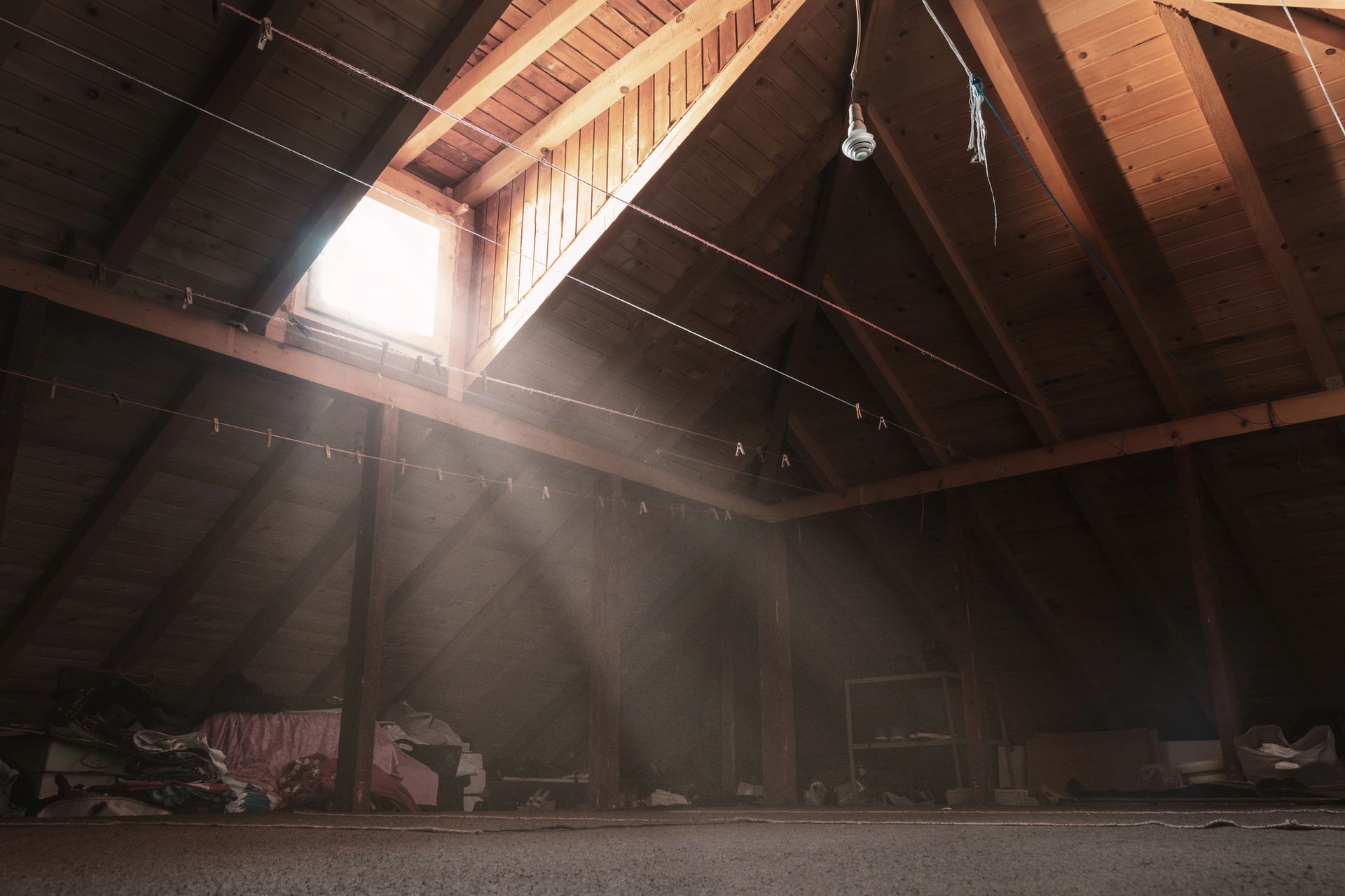 Dusty residential attic space with exposed wooden beams and piles of unwanted belongings requiring professional attic cleanout services in Smyrna GA