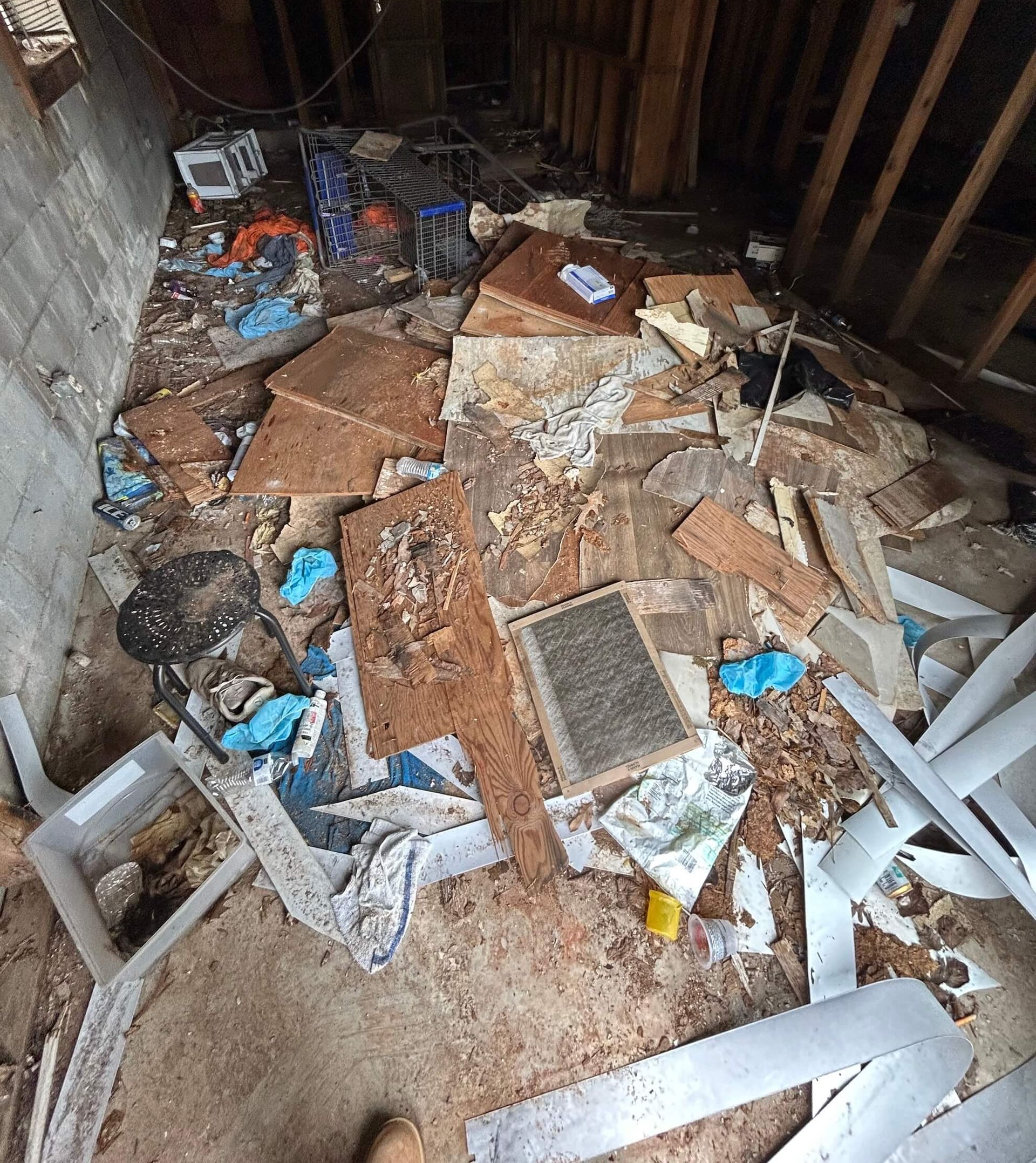 Cluttered attic floor covered with debris, broken boards, and scattered trash; “BEFORE” label at top.