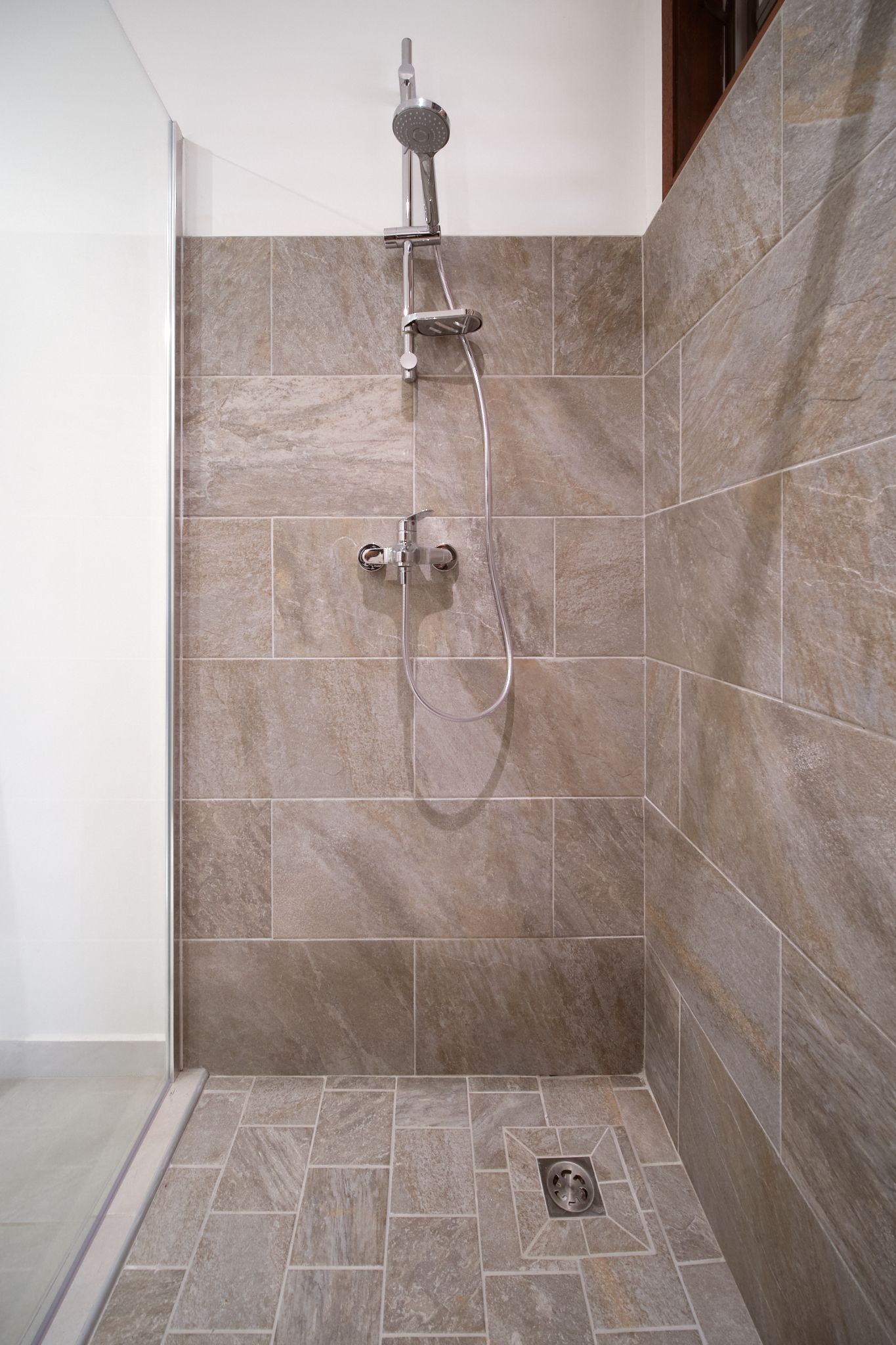 Shower with brown tile walls and floor; chrome showerhead and fixtures.