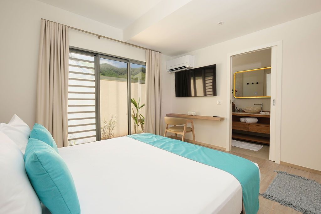 Bedroom with a bed, sliding door, television, and entrance to a bathroom.