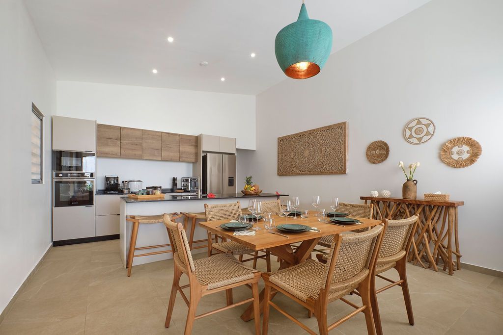 Dining area with a wooden table, woven chairs, and a turquoise pendant light.