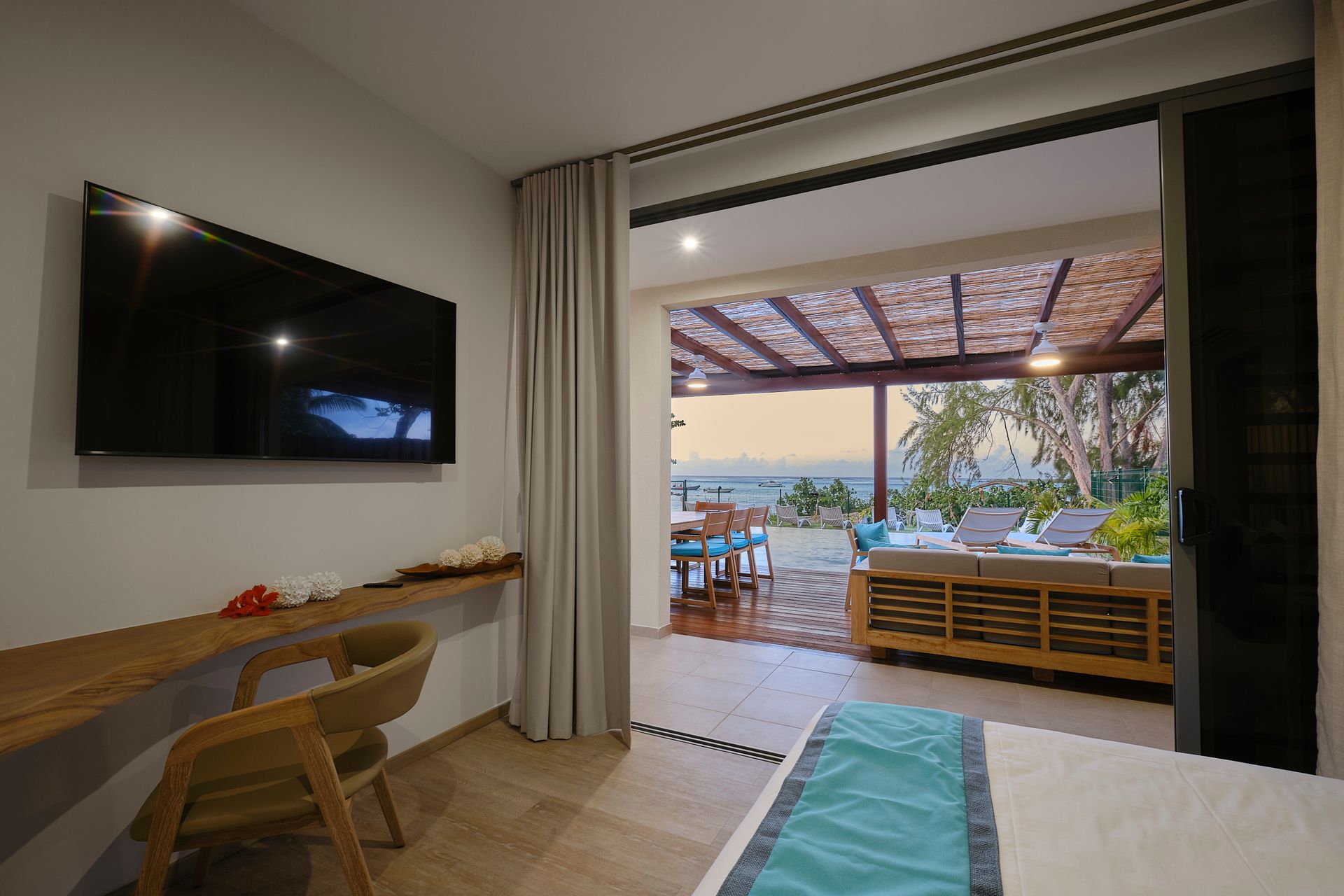 Bedroom with open doors to outdoor seating area with view.