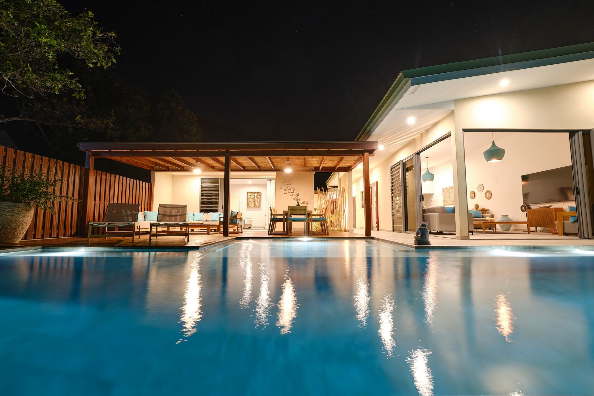 Nighttime view of a pool with a villa in the background, lit with soft lighting.