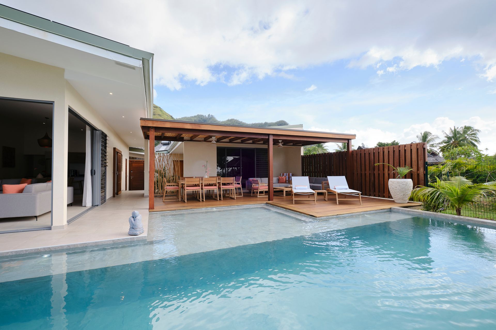 Luxury villa with pool and outdoor dining area on a sunny day.
