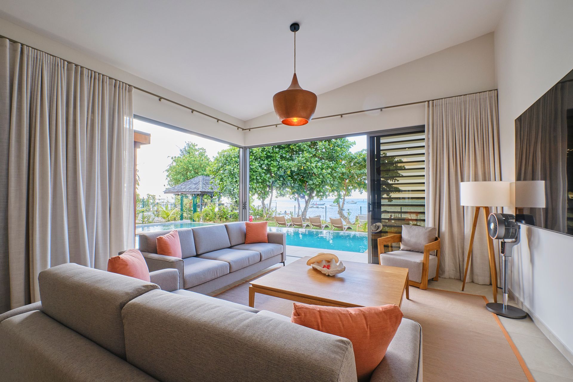 Living room with gray sofas, wood table, and open to a pool.