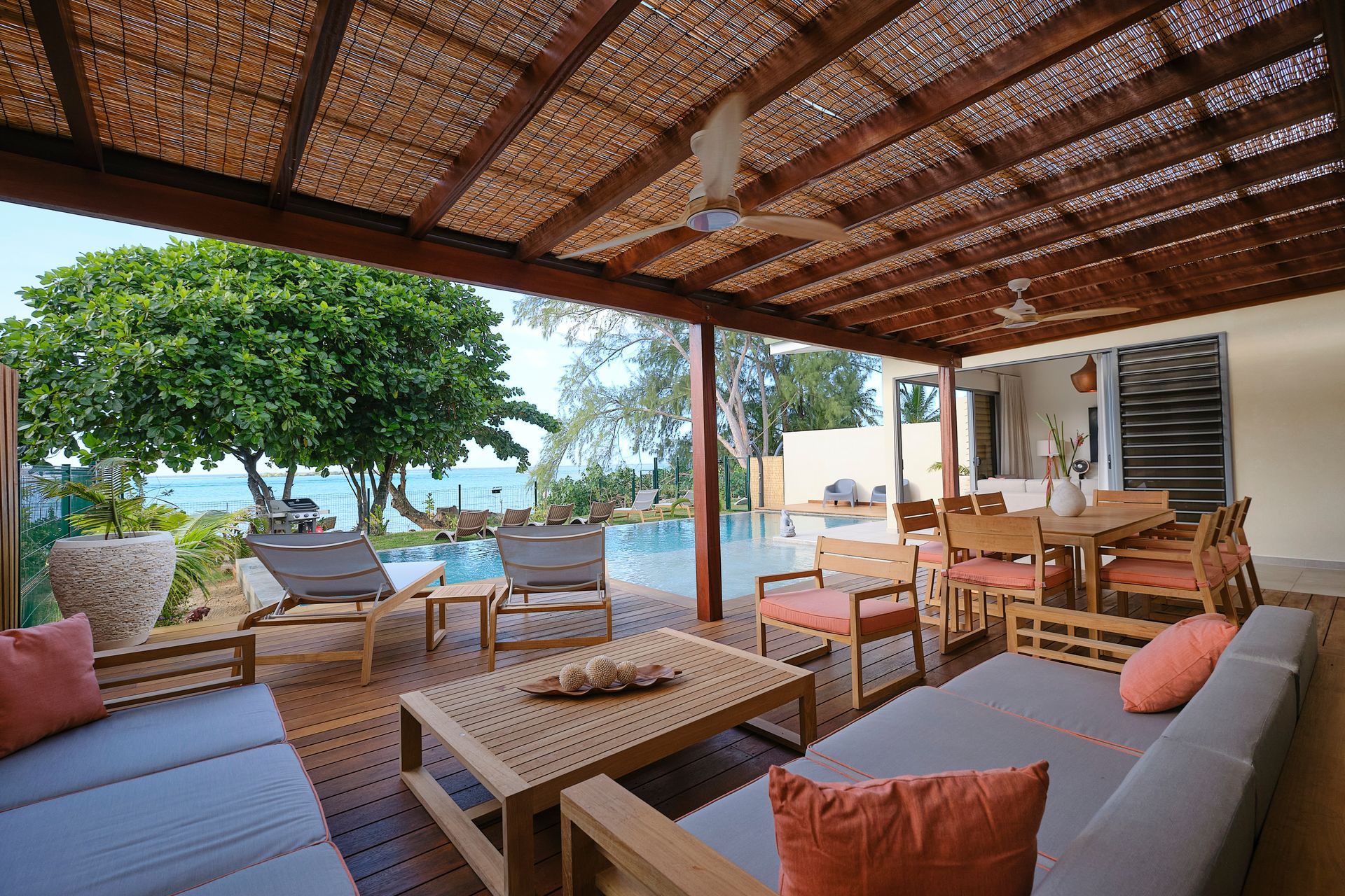 Covered patio with seating, ocean view, and pool.