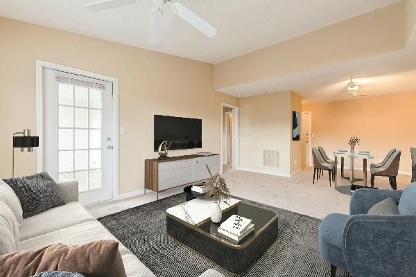 Dining area with glass table, chairs, artwork, and view into kitchen and living room.