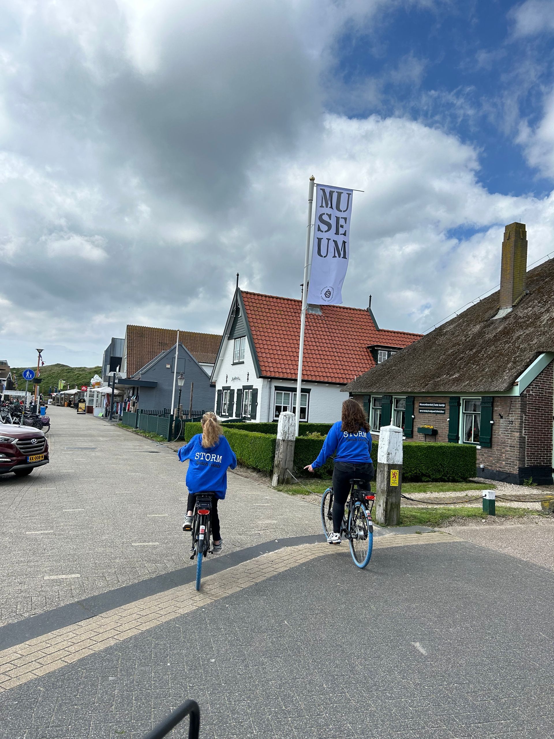 Fietsers rijden op een landweg, een van hen met een blauwe aanhanger met het opschrift