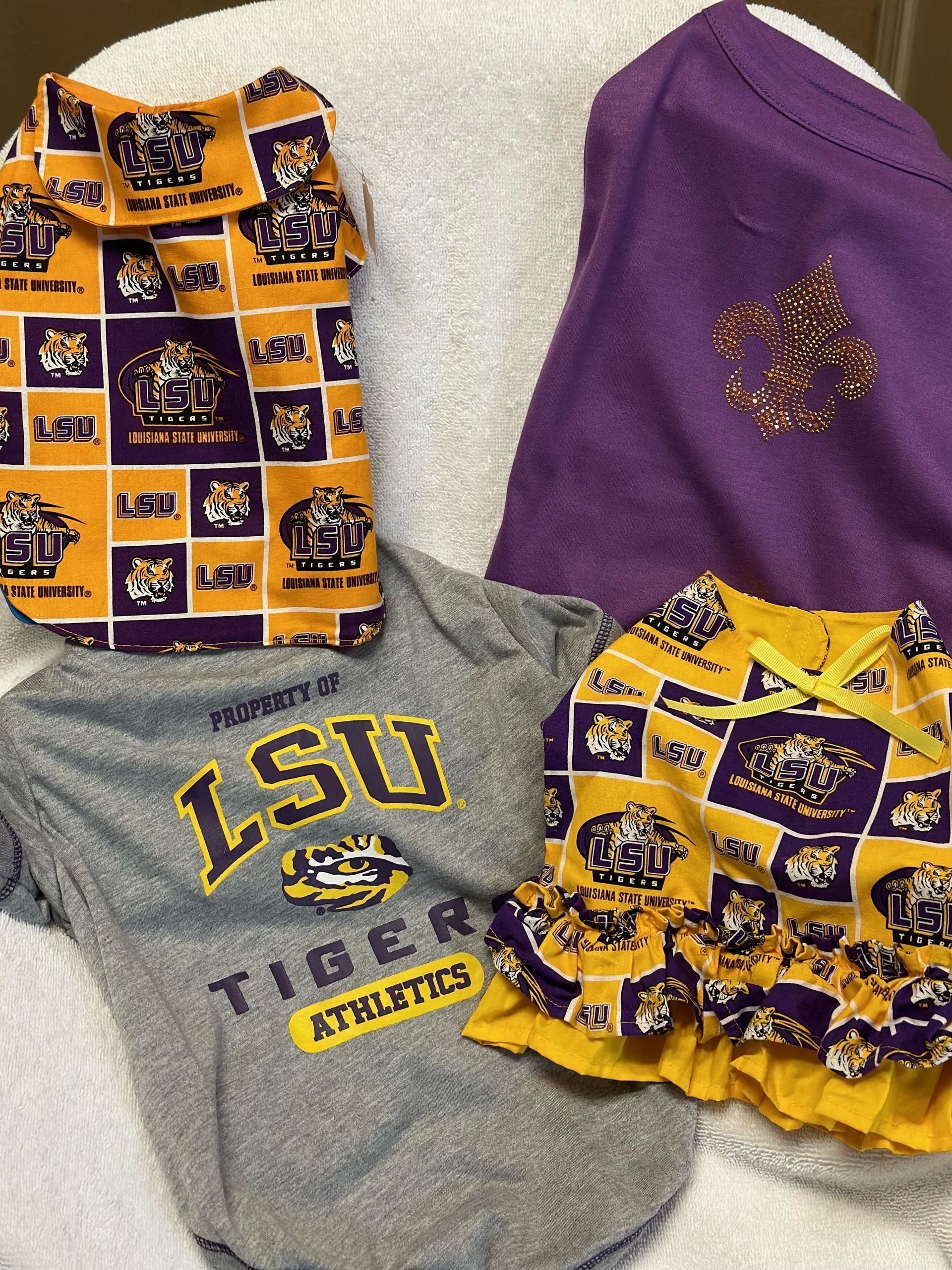 Three lsu athletics shirts are sitting on a white blanket