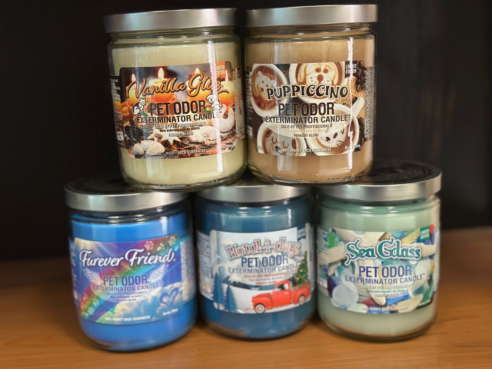 Five jars of candles are stacked on top of each other on a wooden table.