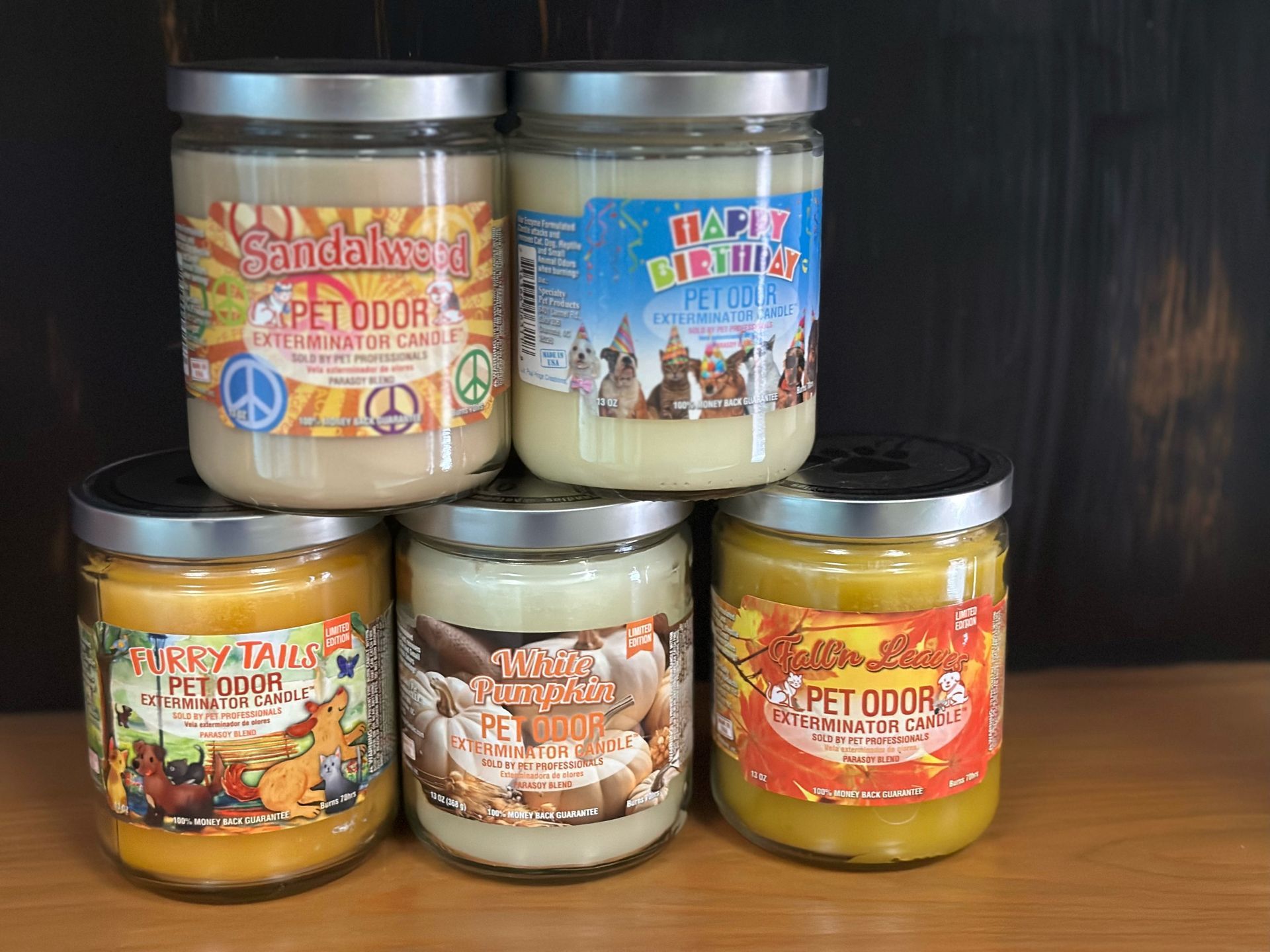 Several jars of candles are stacked on top of each other on a wooden table.