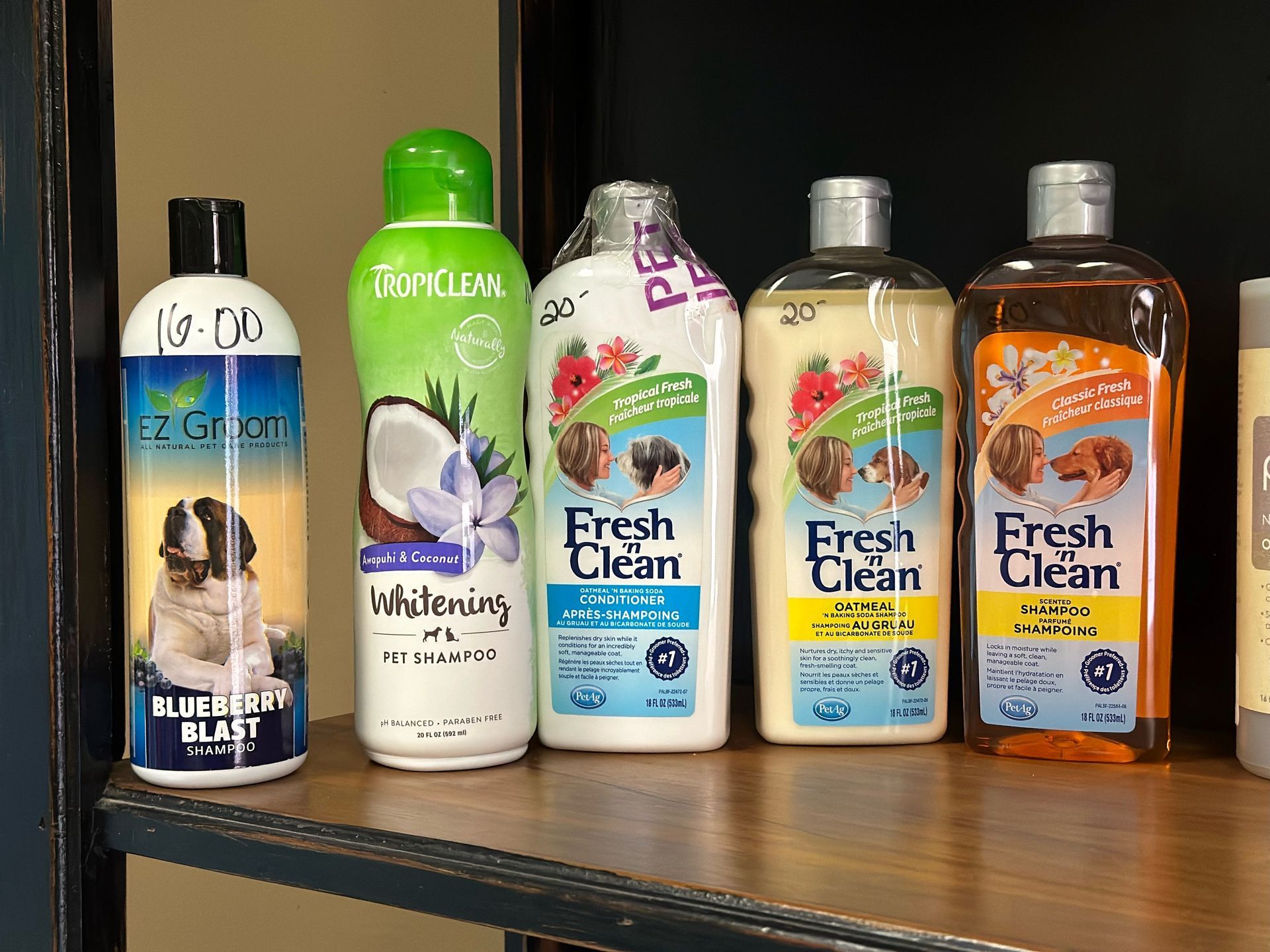 A shelf filled with bottles of dog shampoo and conditioner.