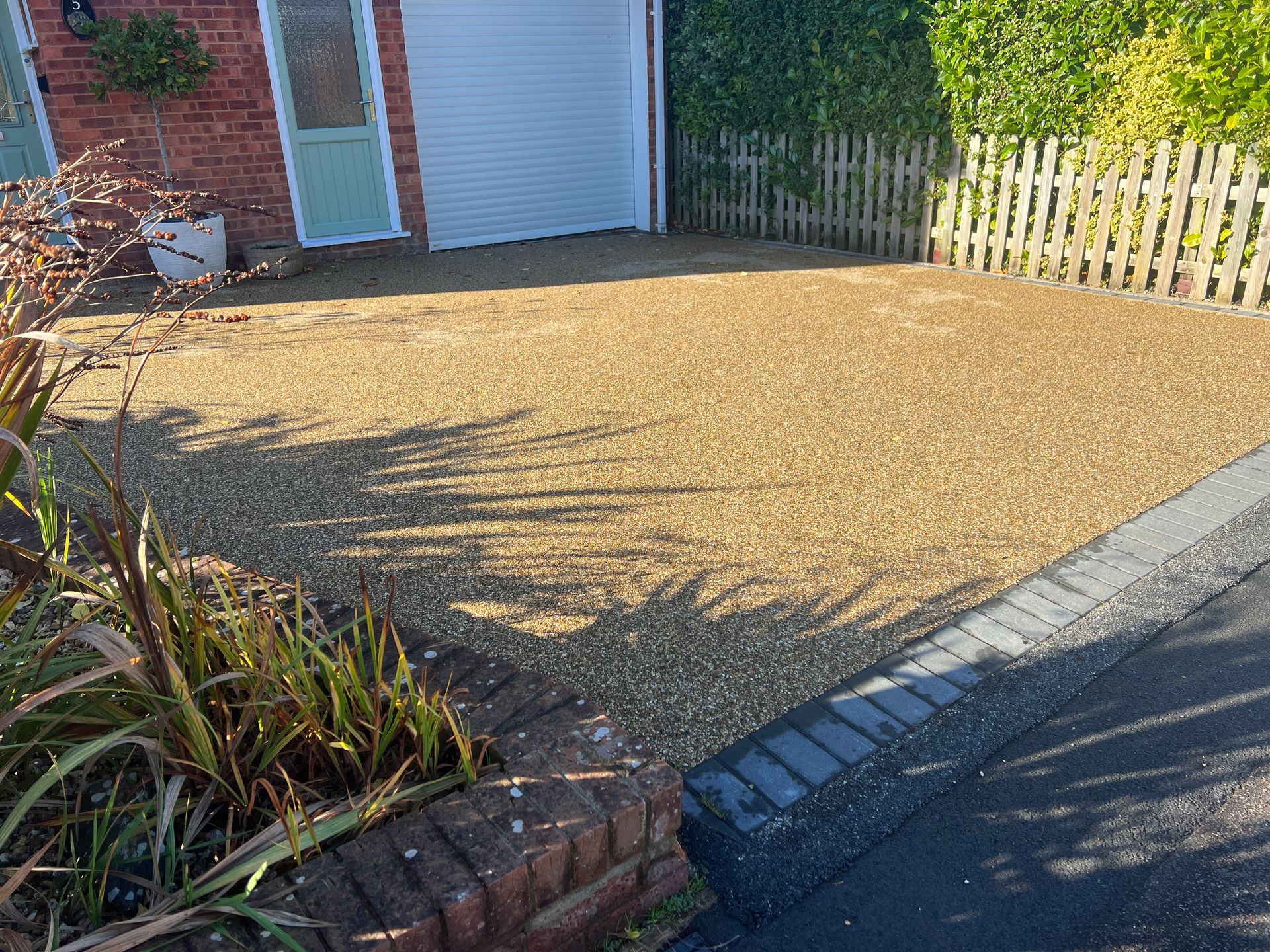 A driveway leading to a house with a garage and a fence.