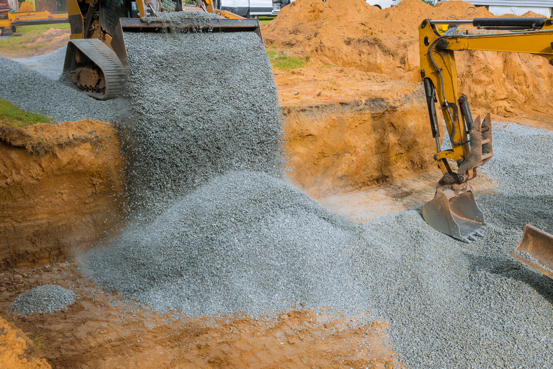 Learn More A yellow excavator is loading gravel into a hole.