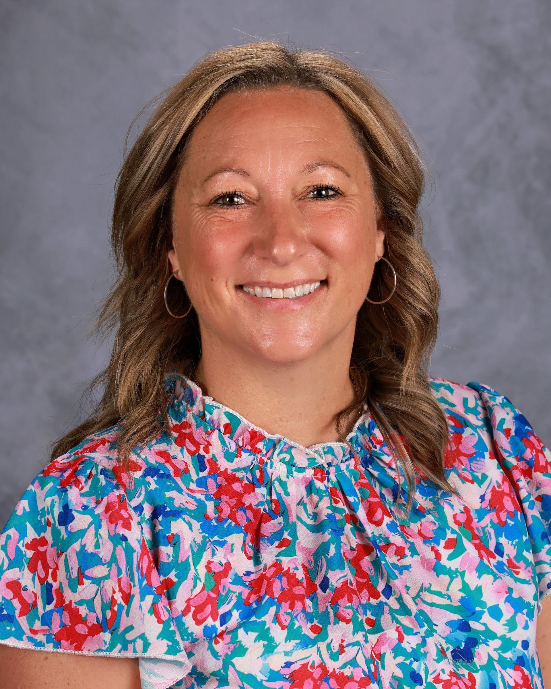 Woman smiling in front of gray backdrop