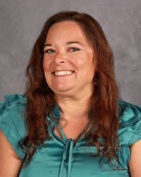 Smiling person in a teal satin top against a gray studio backdrop