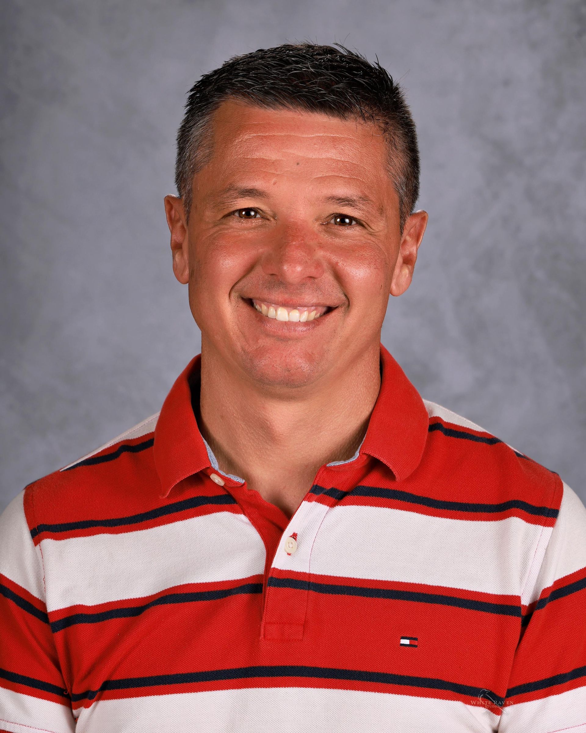 Man smiling in front of gray backdrop