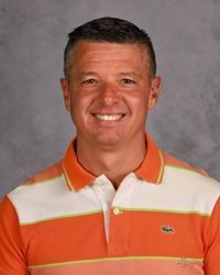 Smiling man in an orange and white striped polo shirt against a gray background