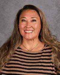 Smiling woman with long hair wearing a striped sweater against a gray studio backdrop