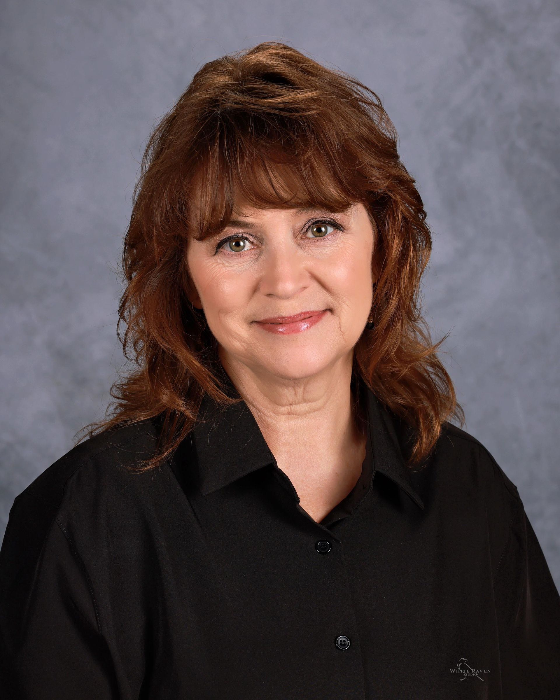Woman smiling in front of gray backdrop