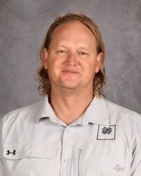 Portrait of a person in a white collared shirt against a gray backdrop