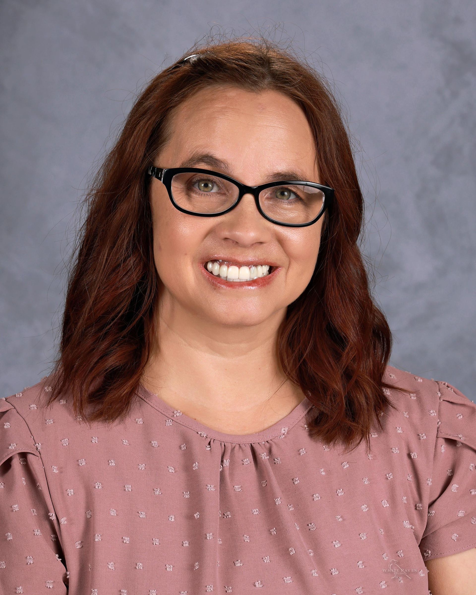 Woman smiling in front of gray backdrop