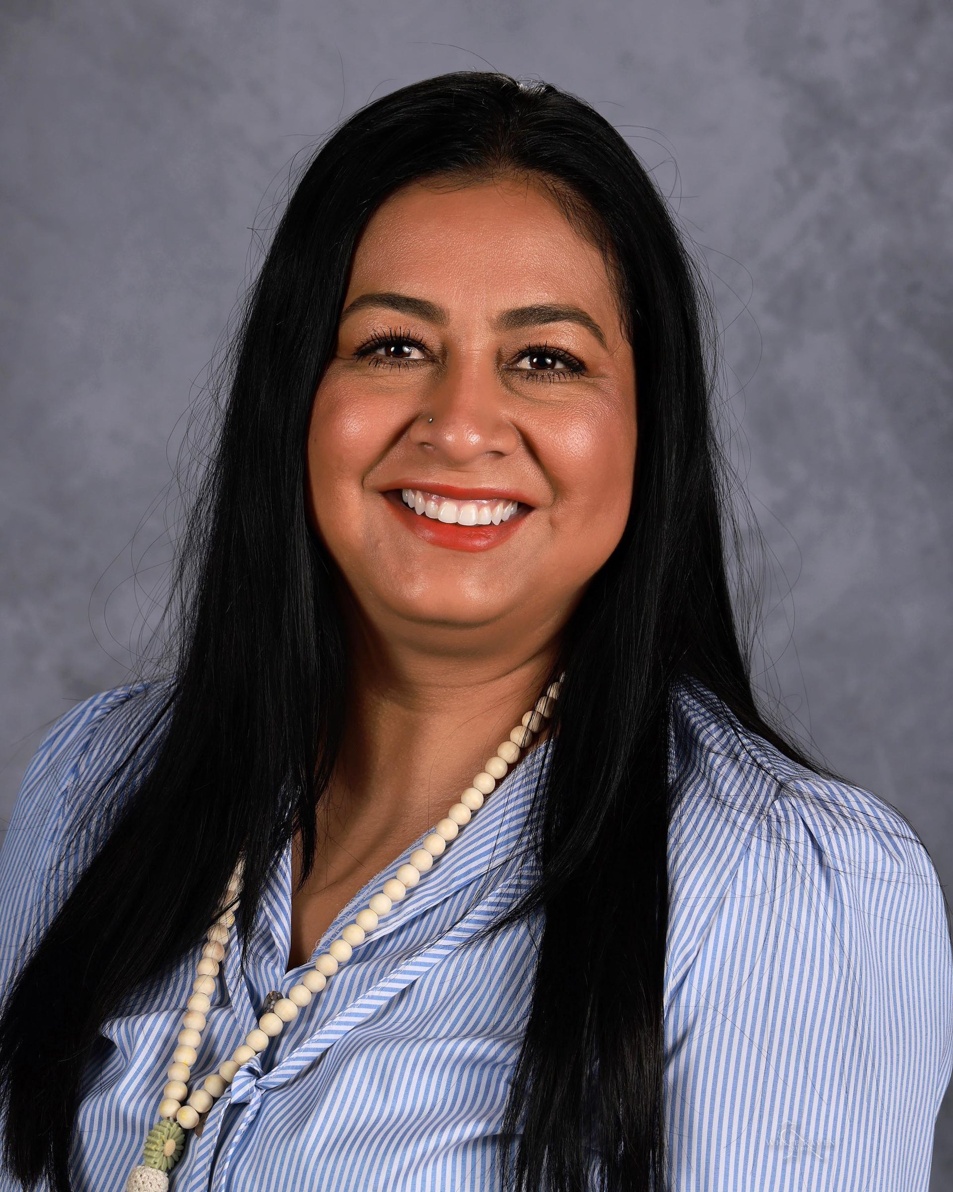 Woman smiling in front of gray backdrop