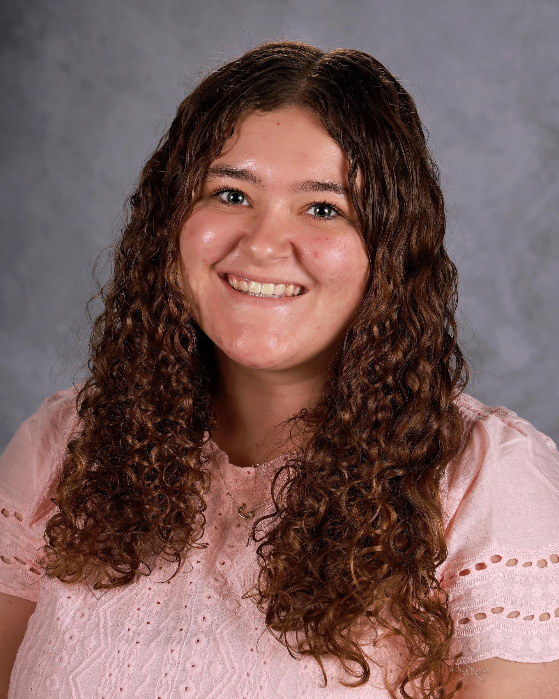 Woman smiling in front of gray backdrop